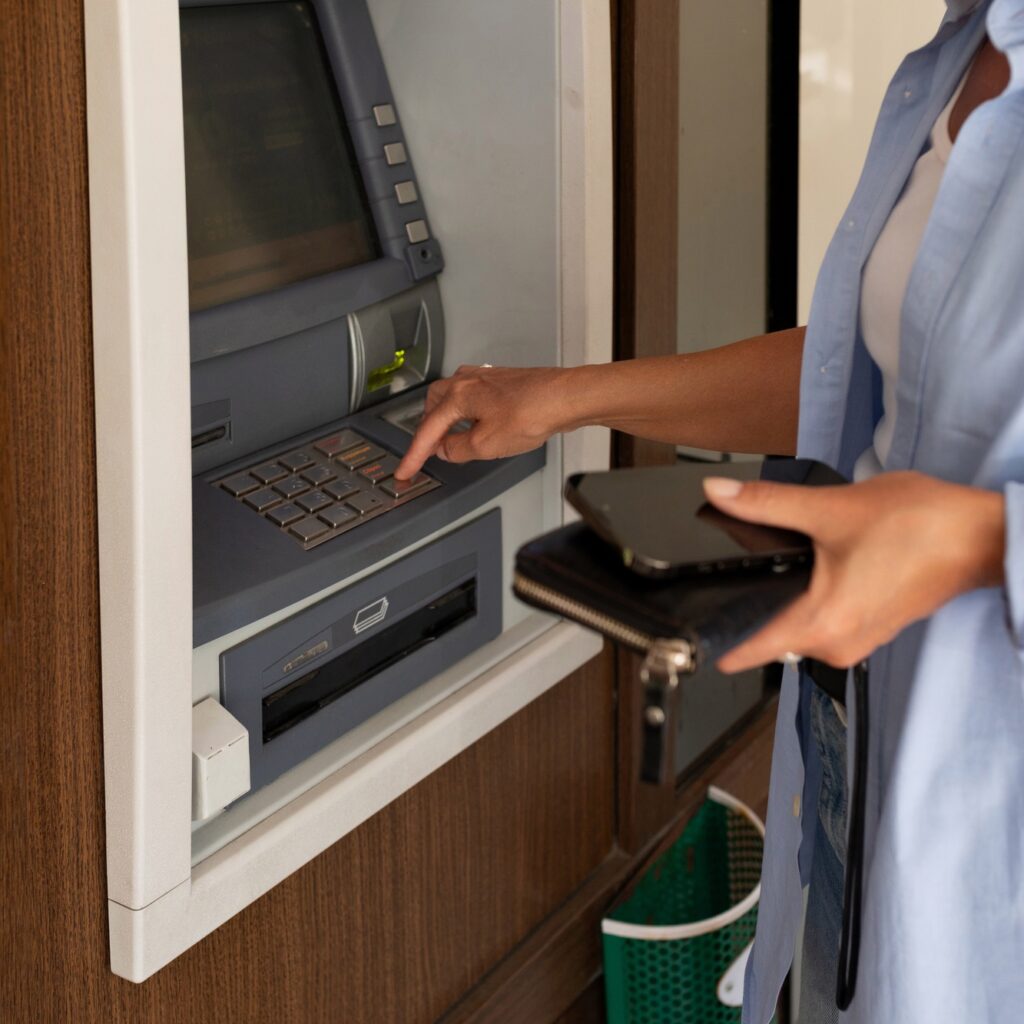 close-up of a woman using an ATM and holding a wallet